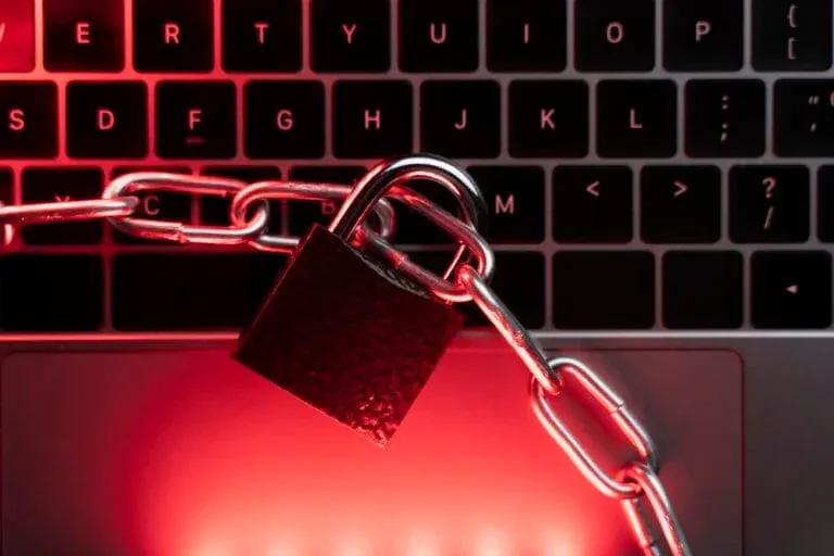 A close-up of a laptop secured with a padlock and chain